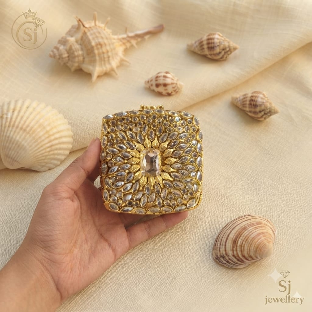Gold-toned Kundan Polki hand clutch with marquise stone detailing held in hand