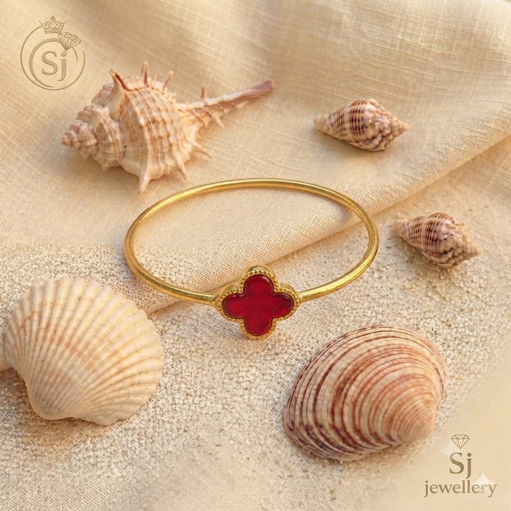 Gold-toned bangle bracelet with red clover enamel charm design