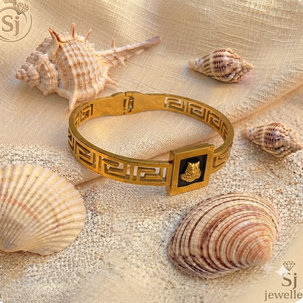 Handcrafted gold-tone bangle cuff with Greek key motif and engraved emblem plaque