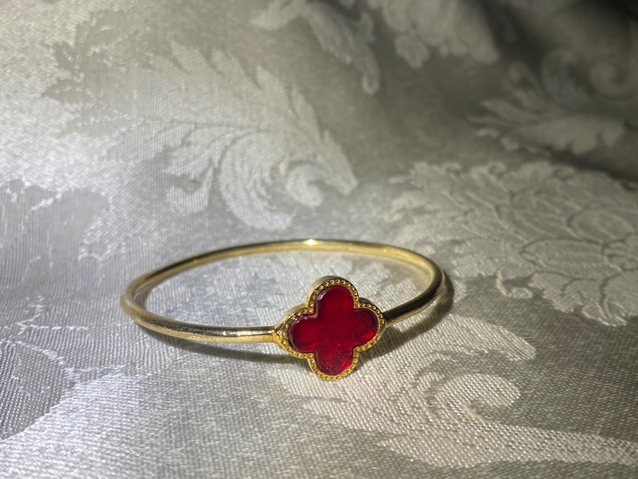 Minimal gold bangle bracelet with red four-leaf clover enamel charm