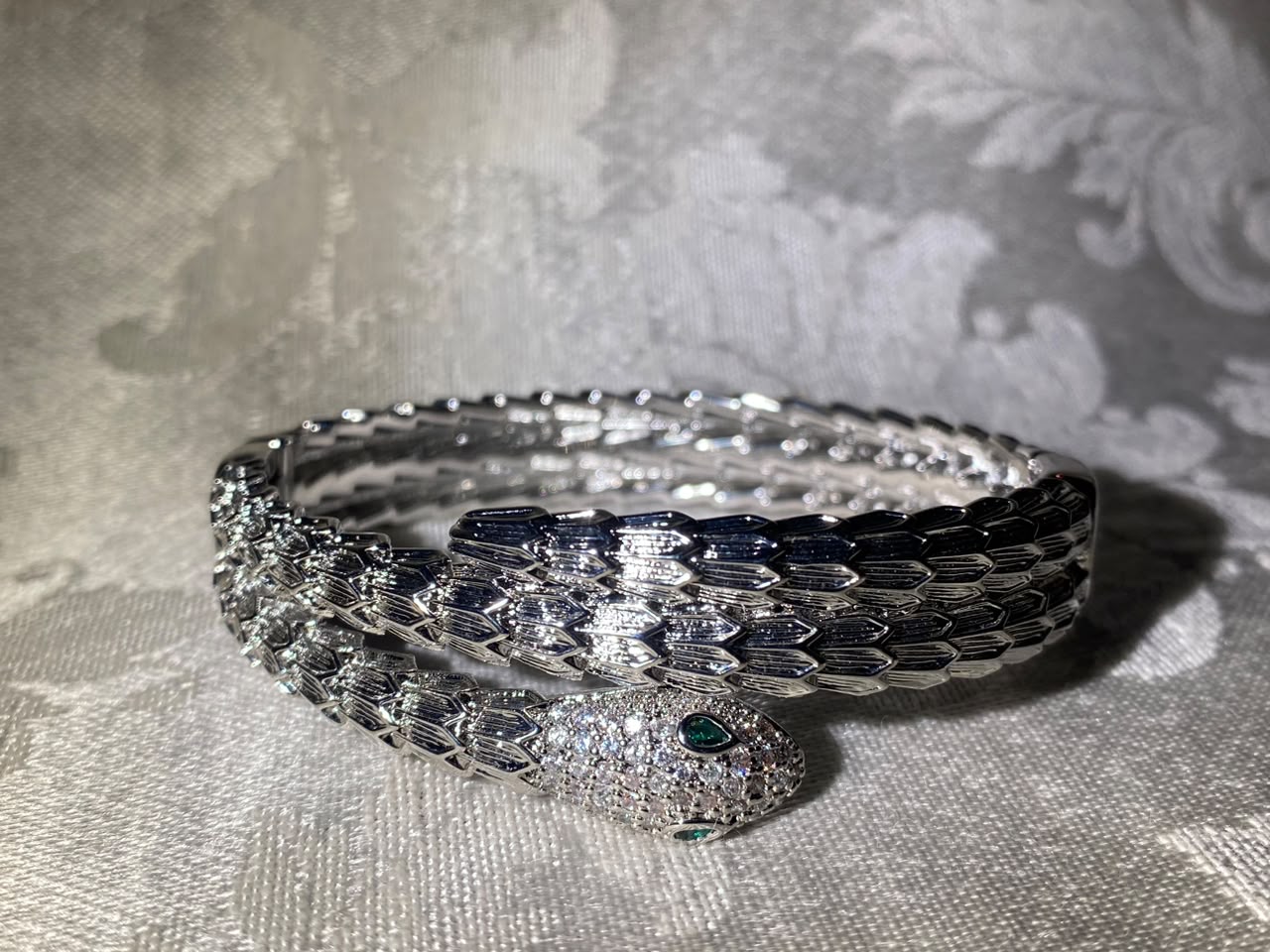 Handcrafted silver-tone snake bangle bracelet with pavé crystal head and emerald eyes